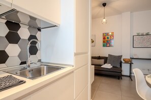 Una cocina moderna con un lavamanos de acero inoxidable, un revestimiento de pared con diseño hexagonal y una lámpara colgante contemporánea.