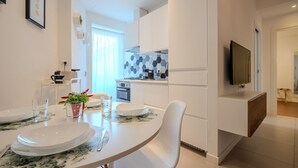 A modern kitchen with white cabinets, a microwave, and a TV mounted on the wall. - Elisa apartment Sistine Chapel (Roma)