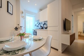 A modern kitchen with white cabinets, a microwave, and a TV mounted on the wall.