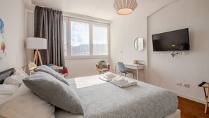 A modern bedroom with a bed, a desk, a chair, a TV, and a window with curtains. - Elisa apartment Sistine Chapel (Roma)