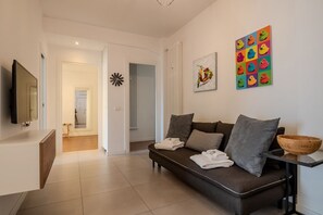 A modern living room with a sofa, a TV, and artwork on the wall.