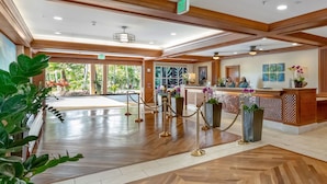 A hotel lobby with a reception desk, a waiting area, and a view of the outdoors.