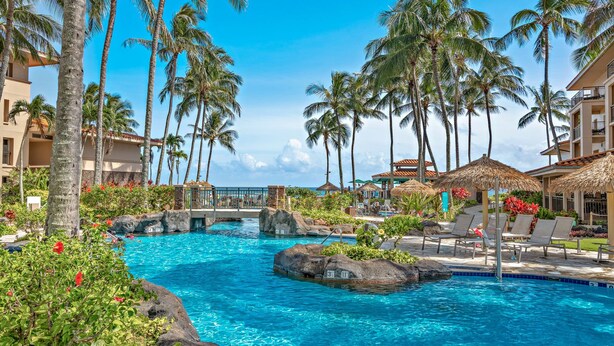 A resort pool with clear blue water, surrounded by palm trees and lounge chairs. - Marriott's Waiohai Beach Club 2BR Islandview Villa (Koloa)