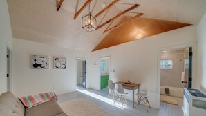 A modern living room with a high ceiling, a dining area, and a visible kitchen.