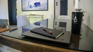 A conference room with a glass table, a laptop, a pen, and a water bottle.