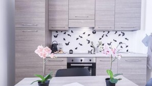Une cuisine moderne avec des meubles de couleur bois clair, un dosseret à motifs noir et blanc et une table à manger agrémentée de deux orchidées en pot.