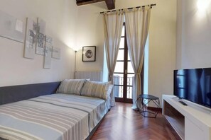 A bedroom with a bed, a TV, a window with curtains, and artwork on the walls. - Italianway - Borgospesso 14 (Milan)