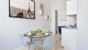 Une cuisine moderne avec des meubles blancs et un coin repas comprenant une table et des chaises en verre.