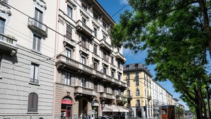 Une rangée de bâtiments historiques dotés de balcons et de devantures de magasins, dont l’un arbore une enseigne visible.
