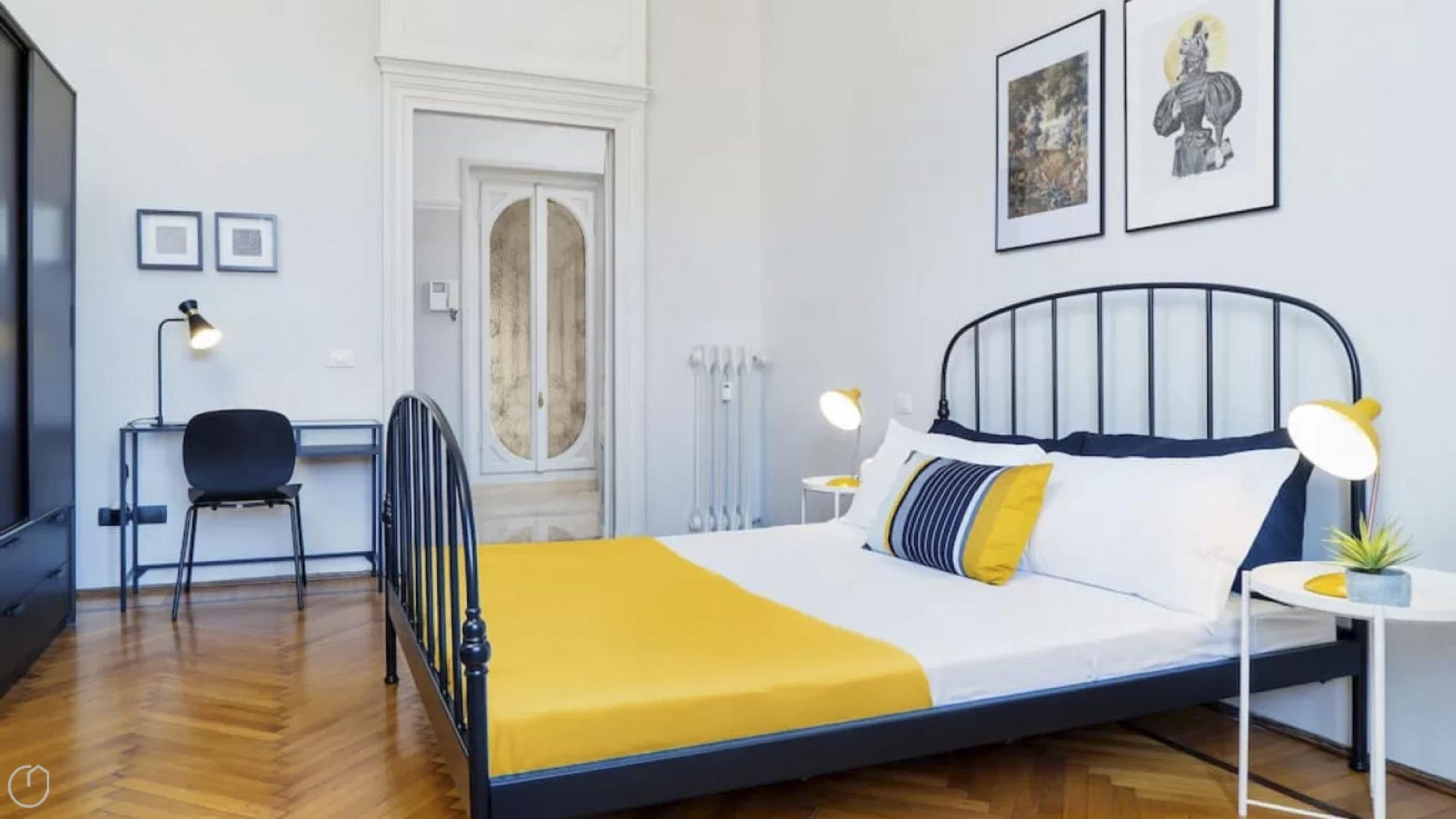 Een slaapkamer met een bed, nachtkastje, lamp, stoel en een bureau met een stoel.