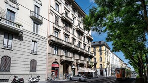 A street view with a row of multi-story buildings, a tram, and parked vehicles. - Italianway - Montello 10 - C (Milan)