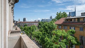 A cityscape with historic buildings, a modern skyscraper, and a tree-lined street. - Italianway - Montello 10 - C (Milan)