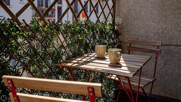 A wooden table with two beige mugs, a red metal chair, and a wooden bench. - Italianway - Bartolini 9 - Piccolo (Milan)