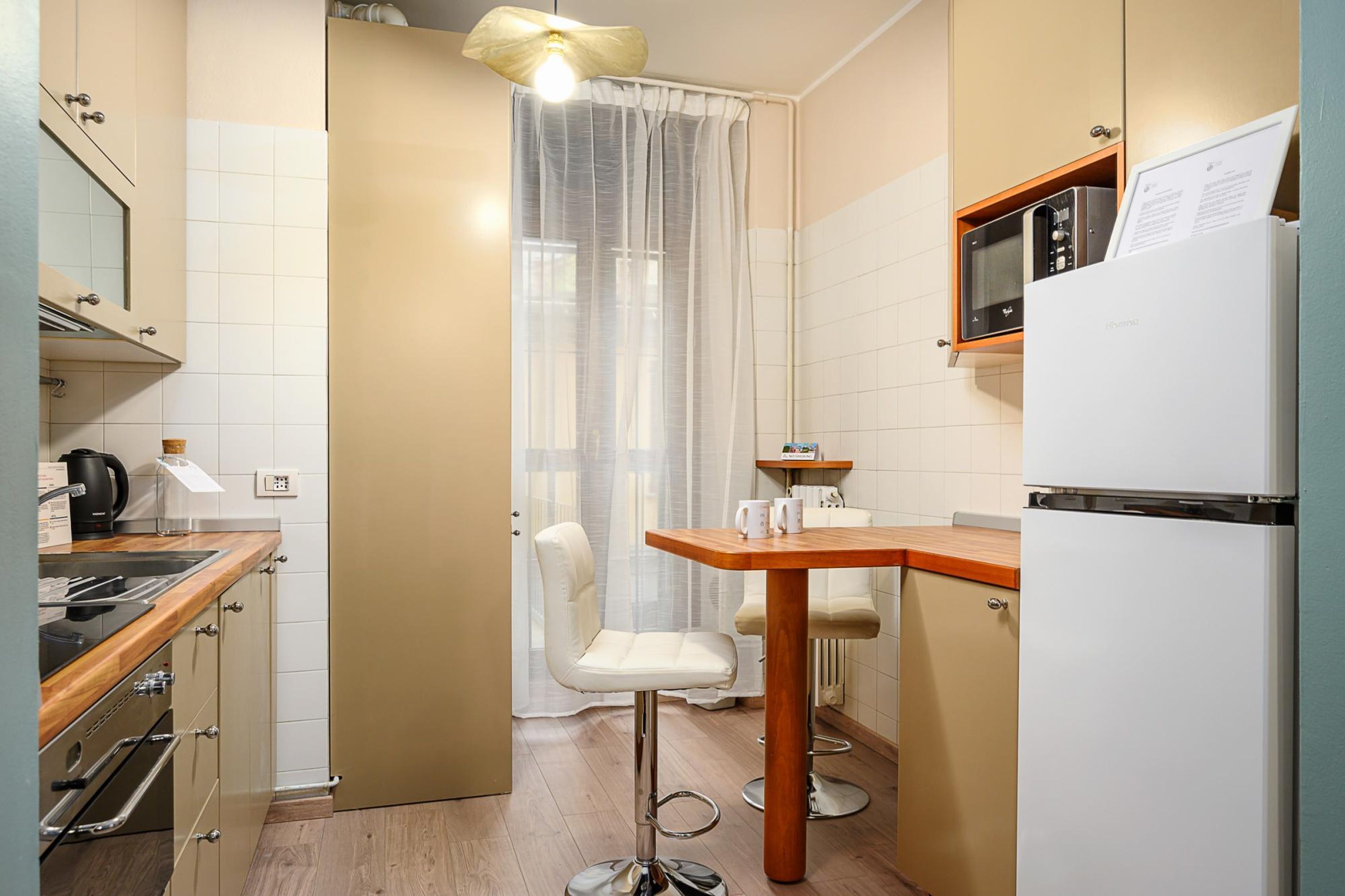 A compact kitchen with a microwave, a refrigerator, a coffee maker, and a small dining table with two chairs.