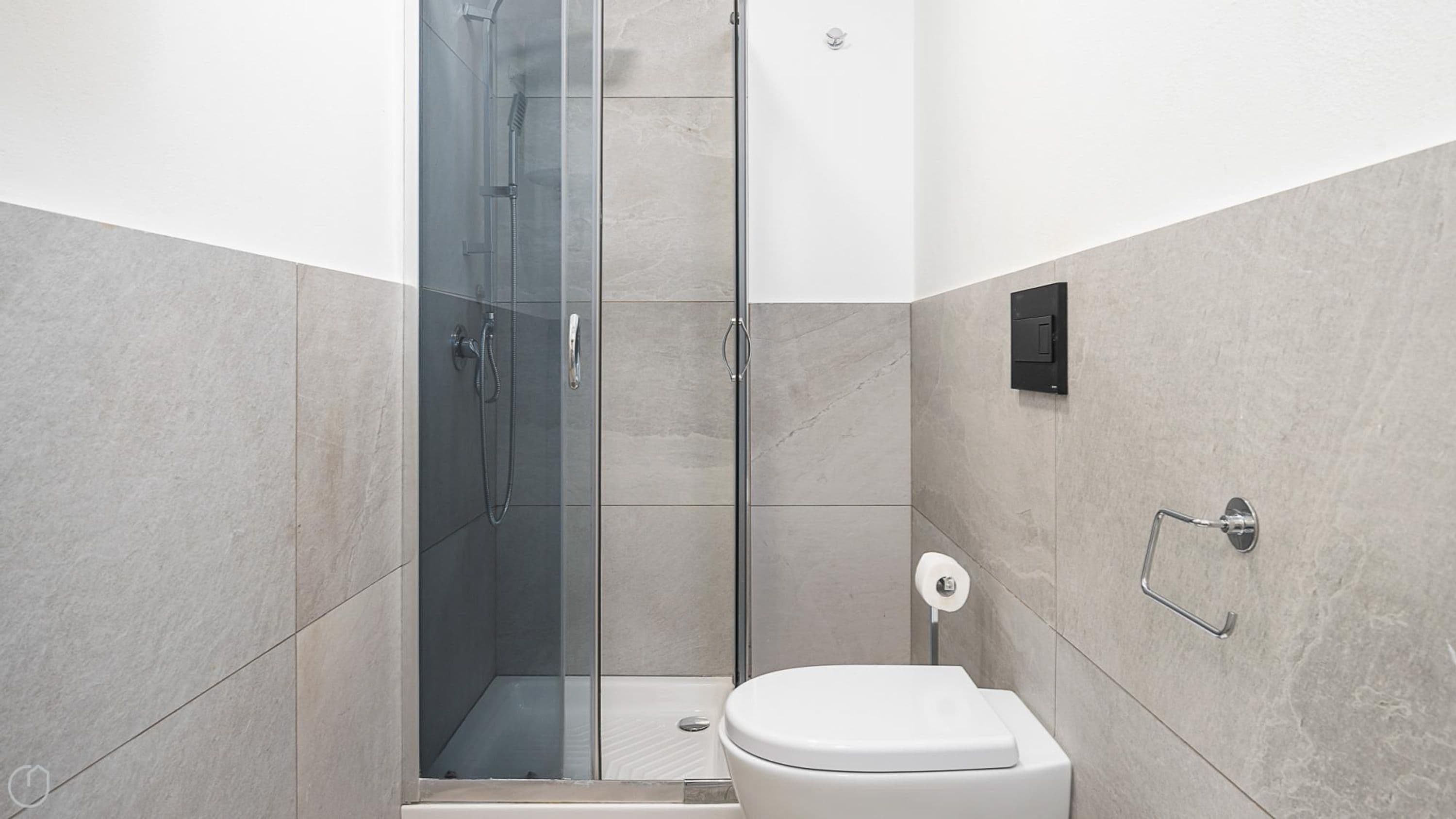 A modern bathroom with a glass-enclosed shower, a toilet, and a towel rack.