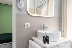 Ein modernes Badezimmer mit einem weißen Waschbecken, einem Spiegel und einem Handtuchhalter.
