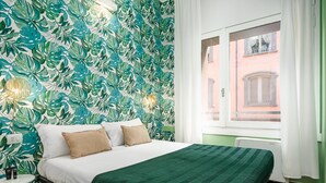 Ein Schlafzimmer mit einem Bett, einer grünen Tagesdecke und einer Wand mit einem Blattmuster.