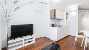 Eine moderne Küche mit weißen Schränken, einem eingebauten Herd und einem Essbereich mit weißem Tisch und Stühlen.