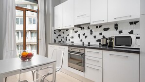 Una cocina moderna con armarios blancos, encimera negra y microondas.