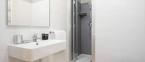A modern bathroom with a white sink, mirror, and shower.