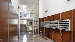 Un pasillo con pared de madera, buzones y una escalera que sube a un nivel superior.