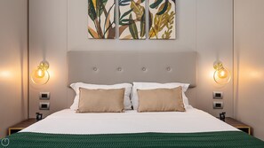 Una cama bien hecha con dos almohadas, un edredón verde y una lámpara fijada a la pared.