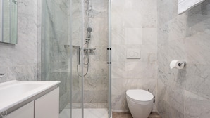 Un baño moderno con cabina de ducha de vidrio, inodoro y lavamanos.