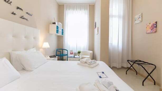 Una camera d'albergo con un letto grande, una scrivania, una sedia, un tavolino e una finestra con tende.