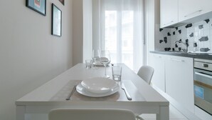 Una cucina moderna con mobili bianchi e una parete rivestita di piastrelle.