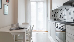 Una cucina moderna con mobili bianchi, un lavello in acciaio inossidabile e uno schienale piastrellato.