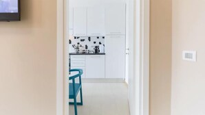Una cucina moderna con mobili bianchi, uno schienale nero e una sedia verde acqua.