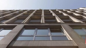 Un edificio a più piani con facciata a griglia, ampie finestre e tetto piatto.