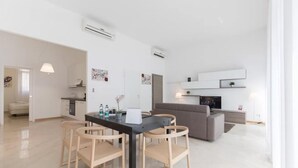 Una sala de estar moderna con comedor, cocina y televisor.