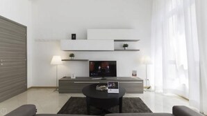 Una sala de estar moderna con un televisor de pantalla plana, una mesa de centro y un sofá.