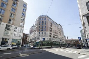 A modern building with a curved corner, large windows, and a tram line running in front. - Italianway Collection - Cannobio 8 - Aida (Milan)