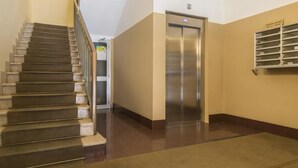 Un vestíbulo de hotel con una escalera, un ascensor y un mueble de almacenamiento en la pared.