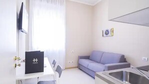 Un espacio habitable compacto con kitchenette, zona de comedor y área de descanso.