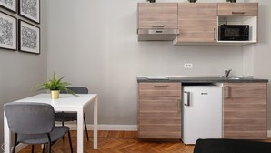 Une petite cuisine équipée d’un four à micro-ondes, d’un petit réfrigérateur et d’un évier. On y trouve également une table à manger avec des chaises et une plante en pot.