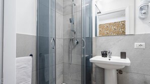 Une salle de bain moderne avec une douche à parois de verre, un lavabo blanc et un miroir décoratif.