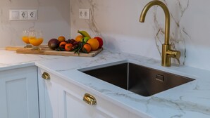 A kitchen with a marble countertop, a sink with a gold faucet, and a fruit display. - Suitur Milenium apartment Marbella beach Venus (MARBELLA)