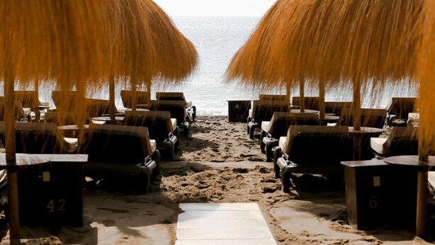 A beach with rows of lounge chairs and umbrellas, a sandy path leading to the sea, and a clear view of the ocean. - Suitur Milenium apartment Marbella beach Venus (MARBELLA)