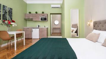Quarto de hotel moderno com cama, escrivaninha, cozinha compacta e banheiro.