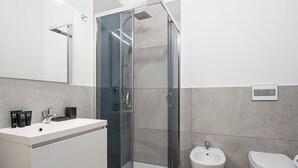 Un bagno moderno con doccia vetrata, lavandino bianco e bidet.
