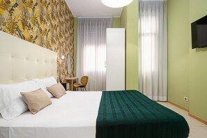 Habitación de hotel con una cama grande, una silla, un escritorio y un armario.