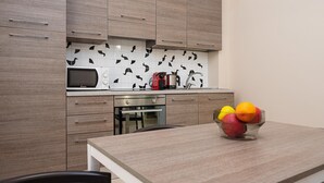 Een moderne keuken met houten kastjes, een magnetron, een waterkoker en een fruitschaal op het aanrecht.