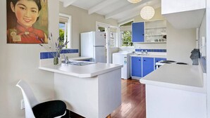 Une cuisine moderne avec des meubles blancs et bleus, un îlot central et un tableau accroché au mur.