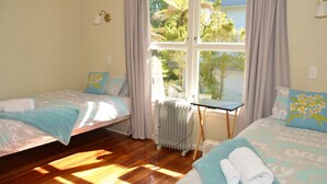 Una habitación con dos camas, un radiador y una mesa.