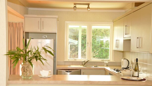 Una cocina moderna con refrigerador empotrado, ventana con vistas a la vegetación y pileta con grifo.