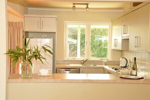 A modern kitchen with a built-in refrigerator, a window with a view of greenery, and a sink with a faucet. - Happiness is Huia a block from the lake - Summer by the lake (Taupo)