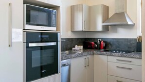A modern kitchen with a built-in microwave, oven, and toaster. There are cabinets and a countertop with a kettle and cups. - Mercy of Lake Taupo- family time + lake time (Taupo)